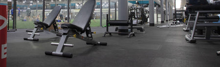 REGUPOL aktivlok interlocking rubber tiles installed under weight benches in a commercial gym