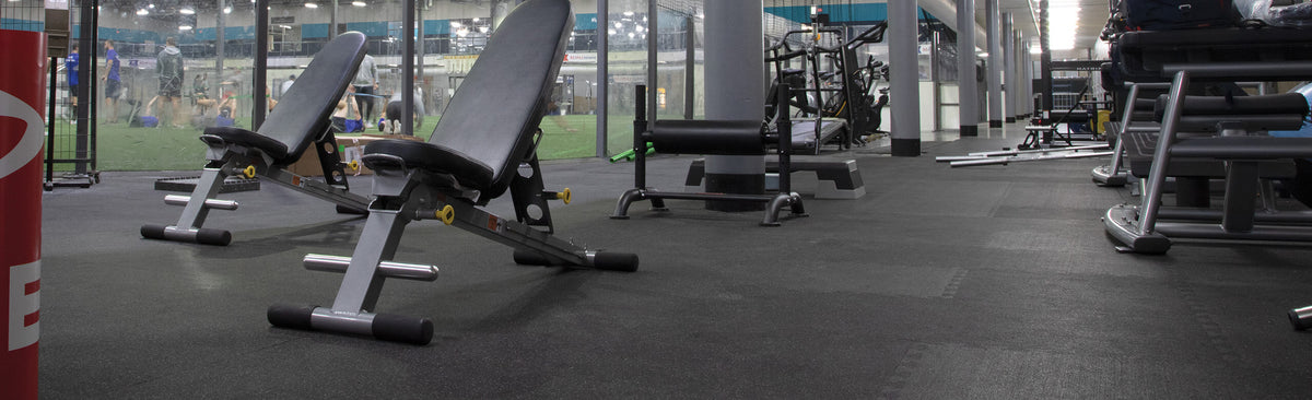 REGUPOL aktivlok interlocking rubber tiles installed under weight benches in a commercial gym