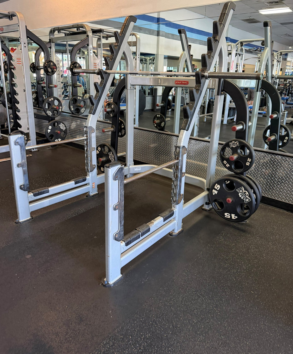 Row of commercial power racks with Olympic plates – used commercial gym equipment package
